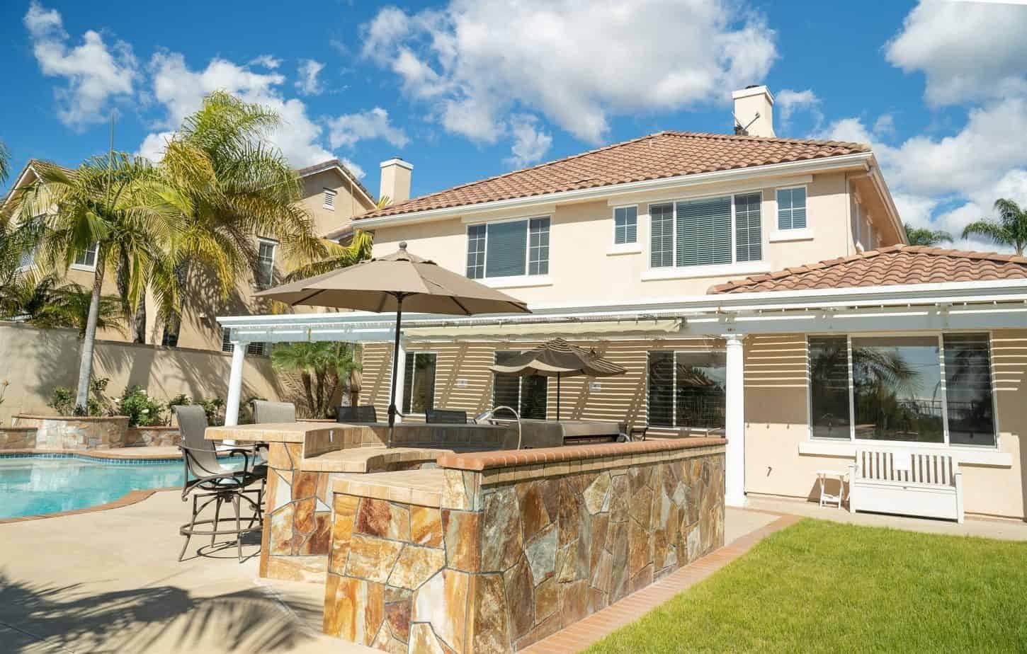 Rear of the residence with covered patio, pool and lawn